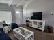 Bright living room with a large TV, white entertainment center, and coastal-themed accents at 5858 Midnight Pass Rd # 27, Sarasota, FL 34242