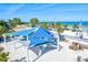 Relaxing beach view featuring blue shade structures, palm trees, and clear ocean waters on a sunny day at 6250 Holmes Blvd # 63, Holmes Beach, FL 34217