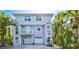 Two-story home exterior featuring light blue siding, a balcony with blue chairs, and lush tropical landscaping at 6250 Holmes Blvd # 63, Holmes Beach, FL 34217