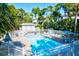 Bright community pool featuring lounge chairs, a sun deck, white picket fence, and lush landscaping at 6250 Holmes Blvd # 63, Holmes Beach, FL 34217