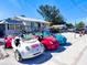 Colorful collection of unique rental vehicles parked in front of a rental shop with surfboards and bikes at 6250 Holmes Blvd # 63, Holmes Beach, FL 34217