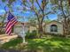 Charming single-story home featuring mature trees, attached garage, well-maintained lawn and an American flag at 6402 23Rd Avenue W Dr, Bradenton, FL 34209