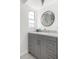 Gray vanity with modern hardware, granite countertops, and a decorative round mirror at 6442 Colonial Dr, Sarasota, FL 34231