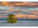 Vibrant image of a yellow lifeguard tower standing on a white sandy beach with a colorful, cloud-filled sky at 6442 Colonial Dr, Sarasota, FL 34231