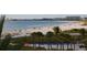 Expansive beach vista with palm trees, blue beach chairs, and a crowded shoreline dotted with people and umbrellas at 6442 Colonial Dr, Sarasota, FL 34231