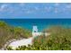 A serene view of a white Adirondack chair by the ocean, set against a backdrop of clear blue skies and calm waters at 6442 Colonial Dr, Sarasota, FL 34231