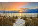 Scenic beach view featuring a sandy path leading to the ocean at sunset, framed by beach grass in the foreground at 6442 Colonial Dr, Sarasota, FL 34231