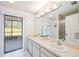 Bright bathroom featuring a double sink vanity, well-lit mirror, and access to an outdoor patio at 6675 Easton Dr, Sarasota, FL 34238