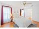 Bright bedroom with a queen bed, soft lighting and a window with sheer curtains and red accents at 6675 Easton Dr, Sarasota, FL 34238