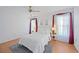 Bright bedroom with a queen bed, soft lighting and a window with sheer curtains and red accents at 6675 Easton Dr, Sarasota, FL 34238
