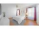 Bright bedroom with a queen bed, soft lighting and a window with sheer curtains and red accents at 6675 Easton Dr, Sarasota, FL 34238