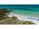 Expansive beach view featuring clear turquoise waters and white sand dotted with colorful umbrellas at 6836 Midnight Pass Rd # 6836, Sarasota, FL 34242