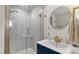 Modern bathroom featuring a glass-enclosed shower, navy blue vanity, and chic, round mirror at 6836 Midnight Pass Rd # 6836, Sarasota, FL 34242