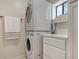 Efficient laundry room with a stacked washer and dryer, complemented by white cabinets and a window at 6836 Midnight Pass Rd # 6836, Sarasota, FL 34242