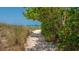 Lush foliage frames a sandy path leading to the beach and crystal clear waters beyond at 6836 Midnight Pass Rd # 6836, Sarasota, FL 34242