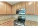 Close-up of stove and microwave, also featuring granite countertops and tile backsplash at 6907 Grand Estuary Trl # 104, Bradenton, FL 34212