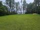 A large grassy backyard with trees, lake, dock and colorful kayaks on the side at 7732 N Mobley Rd, Odessa, FL 33556
