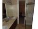 Bathroom featuring double vanity, shower, and view to the bedroom with a bed with gray and white patterned comforter at 7732 N Mobley Rd, Odessa, FL 33556