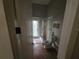 A full bathroom with tile floor, shower and glass doors is seen down a narrow hallway at 7732 N Mobley Rd, Odessa, FL 33556