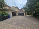 Side view of the home featuring a three car garage and paver driveway at 7732 N Mobley Rd, Odessa, FL 33556