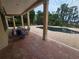 Spacious brick patio leading to a swimming pool with chairs, lush greenery, and lake view at 7732 N Mobley Rd, Odessa, FL 33556