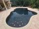 A black pool with triangle accents and brick border with patio furniture surrounding at 7732 N Mobley Rd, Odessa, FL 33556