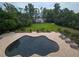 Aerial view of a freeform pool surrounded by brick pavers, lounge chairs, and lush green lawn at 7732 N Mobley Rd, Odessa, FL 33556