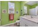 Bright bathroom with green walls, white vanity, and natural light from the window at 8541 Whispering St, Sarasota, FL 34240