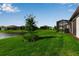 Landscaped backyard featuring a screened lanai, lush green lawn, and views of the pond at 10724 Spring Tide Way, Parrish, FL 34219