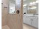 Bathroom showcasing a tiled shower, bronze fixtures, and a view into the double-sink vanity area and additional bathroom space at 10724 Spring Tide Way, Parrish, FL 34219