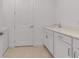 Clean laundry room with white cabinets, solid surface countertop, sink, and modern fixtures, plus tile floor at 10724 Spring Tide Way, Parrish, FL 34219