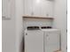 Efficient laundry area showcasing a modern, front-loading washer and dryer set with overhead storage cabinets at 10724 Spring Tide Way, Parrish, FL 34219