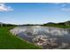 Scenic pond surrounded by lush green lawns and attractive single Gathering homes, clear blue skies at 10724 Spring Tide Way, Parrish, FL 34219