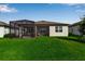Home featuring a screened-in lanai and an outdoor seating area, with a view of the grassy backyard at 10724 Spring Tide Way, Parrish, FL 34219