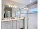 Modern bathroom featuring double sinks, a large mirror, stylish lighting, and a glass-enclosed shower at 11015 High Noon Trl, Parrish, FL 34219