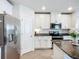 Kitchen with stainless steel refrigerator and appliances, white cabinets and dark countertops at 11015 High Noon Trl, Parrish, FL 34219