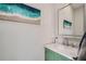 Stylish bathroom with a green vanity, marble countertop, modern faucet, and elegant beach-themed artwork at 11367 Perico Isle Cir, Bradenton, FL 34209