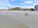 Beach scene with two women relaxing in blue beach chairs near hotels and palm trees at 116 Vista Hermosa Cir # 204C, Sarasota, FL 34242