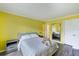 Bright yellow bedroom features a queen bed with gray bedding, nightstand, and a full-length mirror at 116 Vista Hermosa Cir # 204C, Sarasota, FL 34242