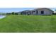 Spacious green backyard with a lovely lake view and screened-in porch on a sunny day at 12007 Clubhouse Dr, Lakewood Ranch, FL 34202