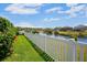 Lush backyard overlooking tranquil pond with white picket fence and vibrant flowers at 12214 Streambed Dr, Riverview, FL 33579