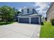 Beautiful blue home featuring a three car garage, green lawn and bright blue skies at 12214 Streambed Dr, Riverview, FL 33579