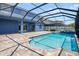 Backyard oasis with a screened in pool, spa, and brick pavers plus a view of the blue home at 12214 Streambed Dr, Riverview, FL 33579