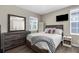 Cozy bedroom with a wooden dresser, mirror, and comfortable bed under a bright window at 12520 Shimmering Oak Cir, Venice, FL 34293