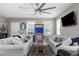 Cozy living room with white sofas, modern ceiling fan, and a wall-mounted TV for entertainment at 12520 Shimmering Oak Cir, Venice, FL 34293