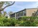 A serene exterior view shows a multi-story building with large windows and balconies surrounded by lush greenery at 1609 Bayhouse Point Dr # 232, Sarasota, FL 34231