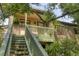 Two-story home featuring an elevated, wooden staircase and a covered balcony framed by lush greenery at 1609 Bayhouse Point Dr # 232, Sarasota, FL 34231