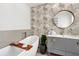 Stylish bathroom with palm wallpaper, round mirror, grey vanity, and free standing tub at 174 Golden Gate Pt # 21, Sarasota, FL 34236