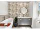 Stylish bathroom with palm wallpaper, round mirror, grey vanity, and free standing tub at 174 Golden Gate Pt # 21, Sarasota, FL 34236