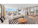 Bright living room with contemporary furnishings, stylish rug, and gorgeous water views from expansive windows at 174 Golden Gate Pt # 21, Sarasota, FL 34236